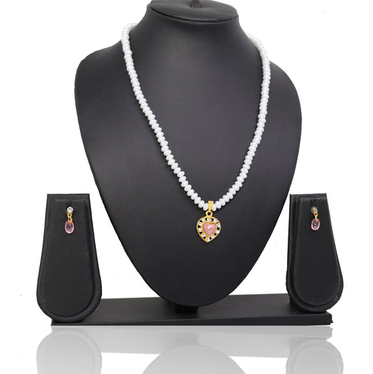 A pearl coral pendant set displayed on a necklace with a pair of matching earrings, set on a black stand with a mannequin bust.