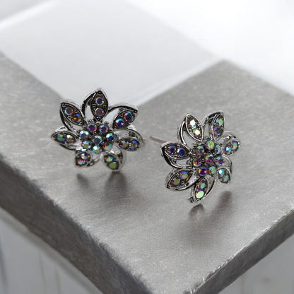 A pair of silver stud earrings designed in the shape of a flower with multicolored gemstones set in them.