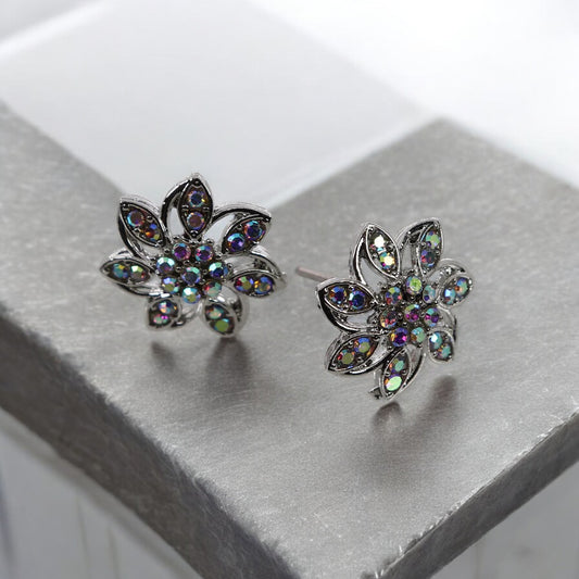 A pair of silver stud earrings designed in the shape of a flower with multicolored gemstones set in them.