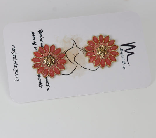 A pair of orange floral stud earrings displayed on a white card with 'Magical Wings' branding.