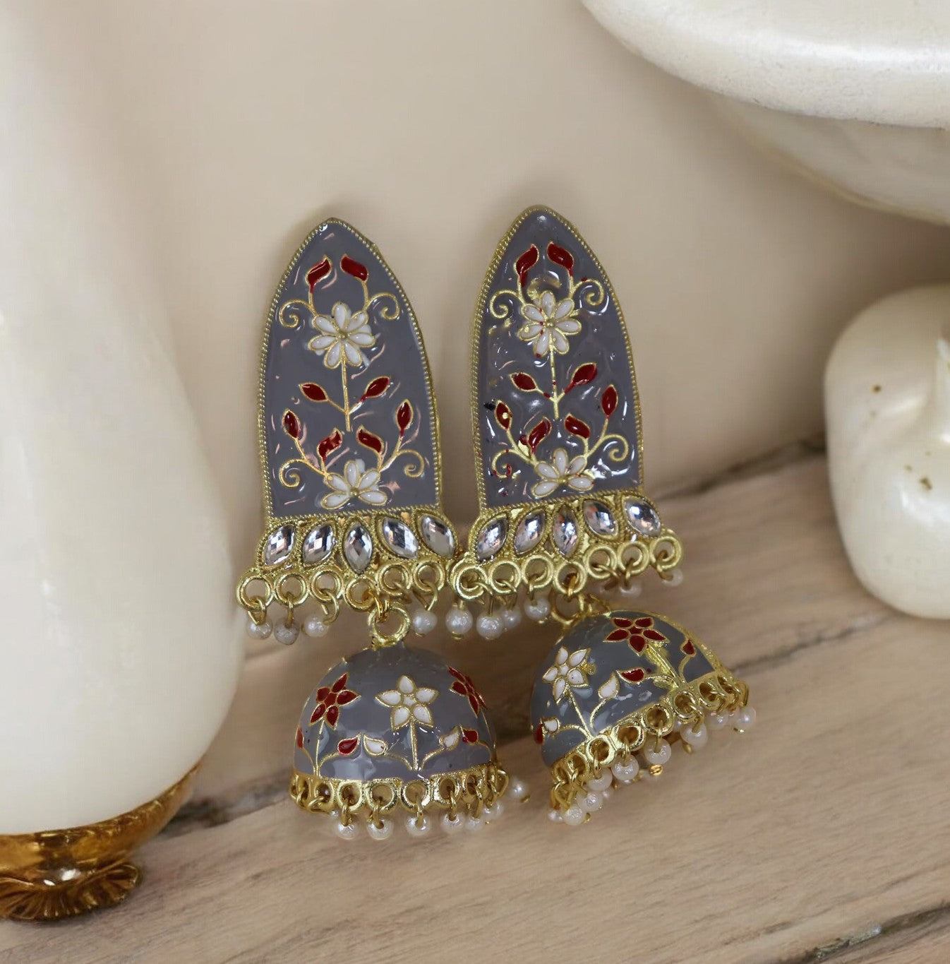 A pair of gray Meenakari earrings with floral patterns and gold accents, displayed against a white background.