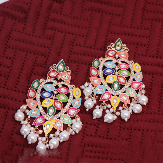 A pair of multicolored Chandbali earrings with pearl drops, displayed against a red background.