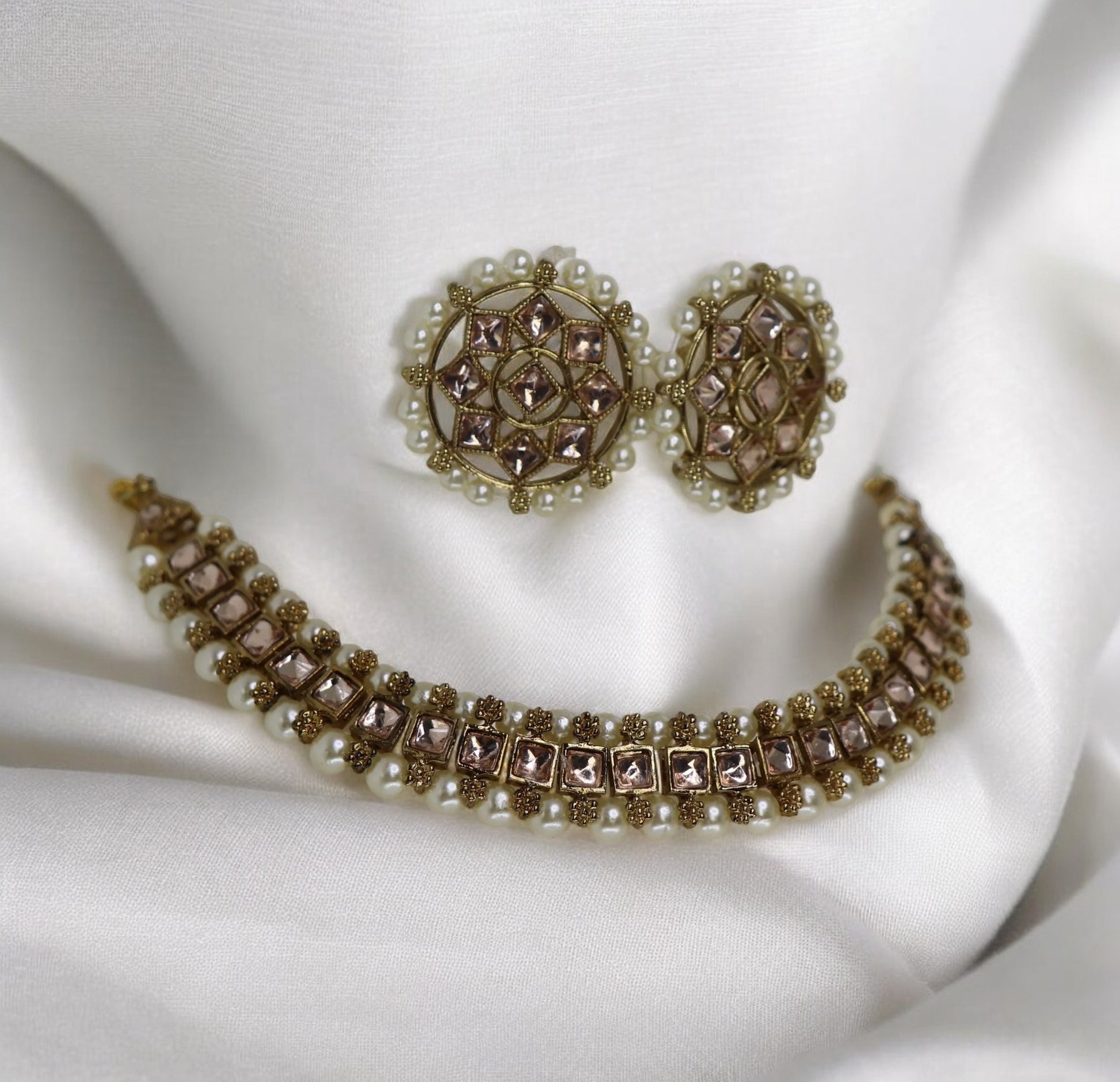 A set of jewellery including a choker necklace and earrings, adorned with clear kundan-style stones and intricate designs.