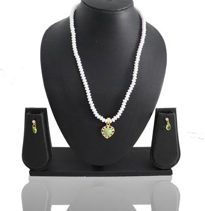 A pearl jade pendant set displayed on a black stand, including a necklace and earrings with a green and gold colored pendant.