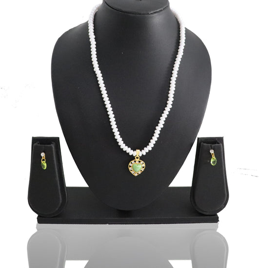 A pearl jade pendant set displayed on a black stand, including a necklace and earrings with a green and gold colored pendant.