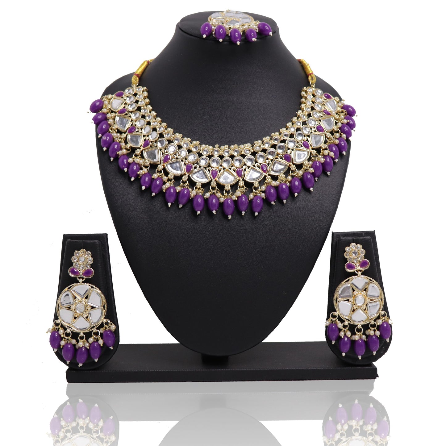 A violet bead mirror necklace set with a mangtikka and earrings displayed on a black stand.