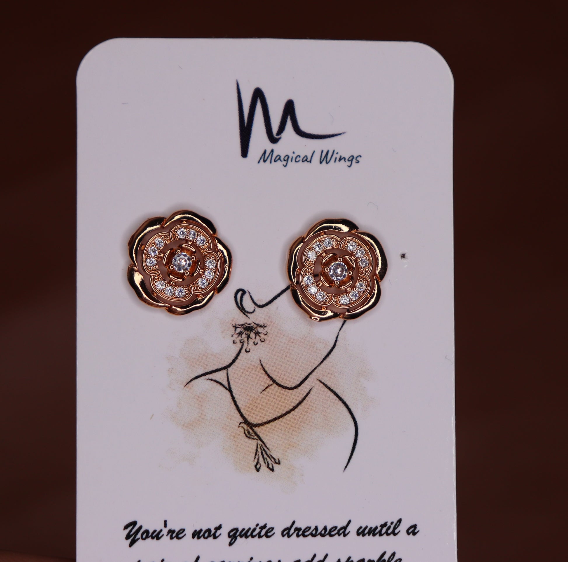 A pair of stud earrings with rose gold and white gold color scheme, featuring floral patterns and adorned with diamonds, presented on a branded card.