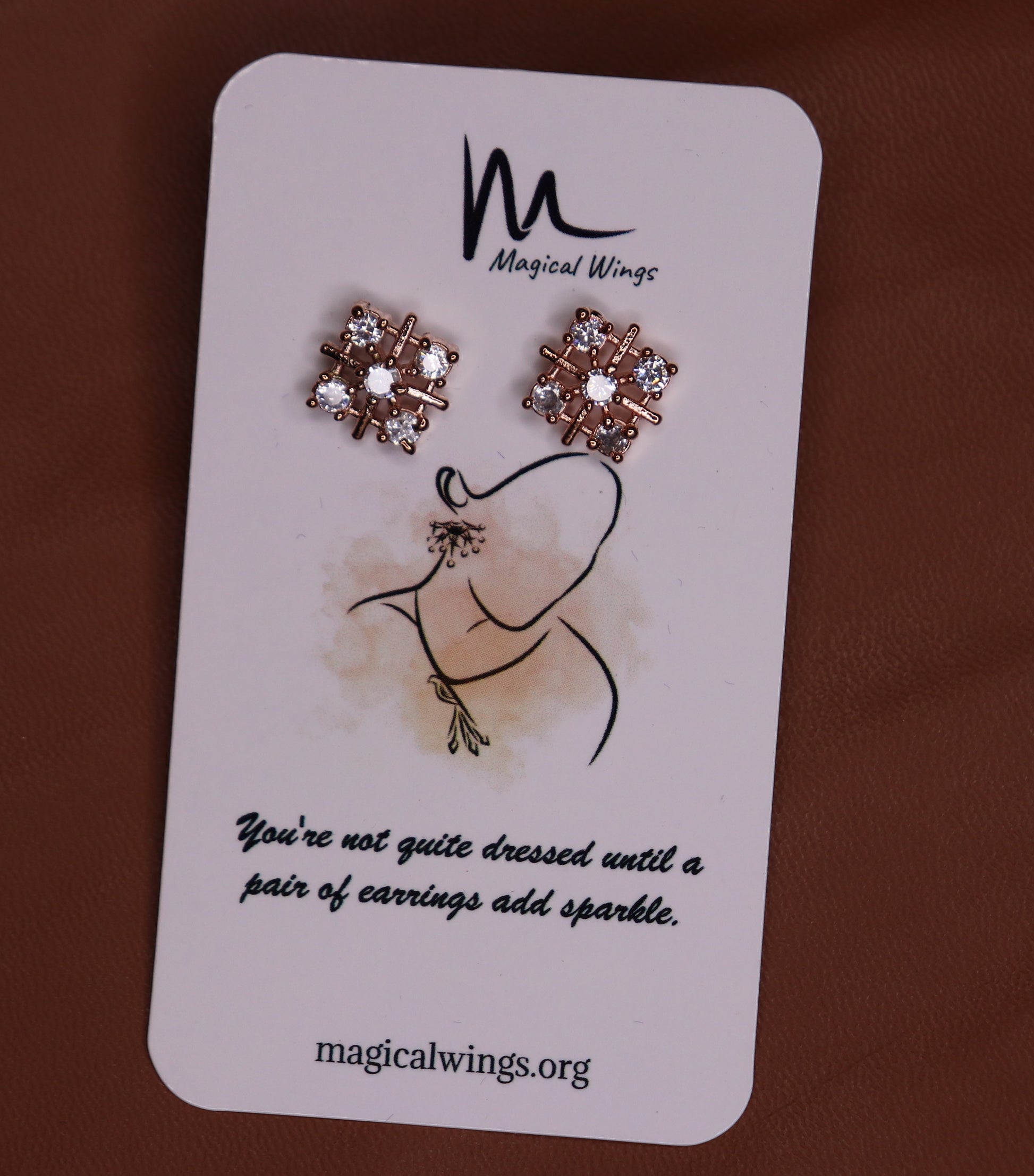 A pair of floral stud earrings with AD embellishments presented on a card with 'Magical Wings' branding.