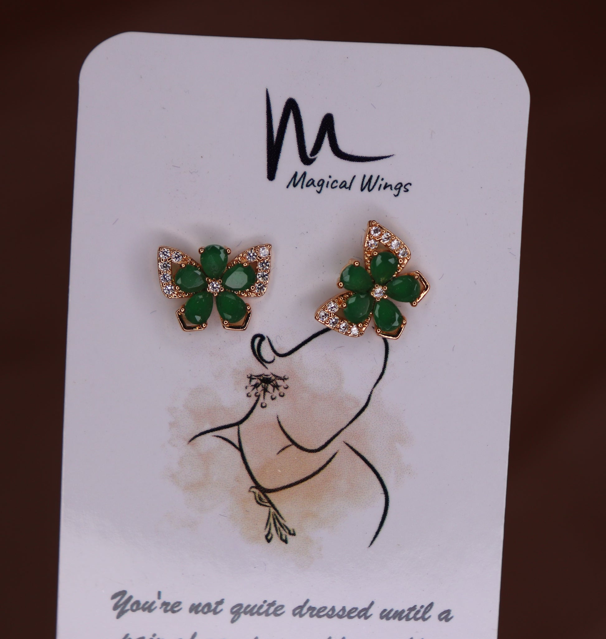 A pair of green butterfly-shaped stud earrings on a card with 'Magical Wings' branding.