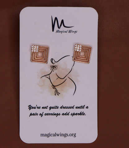 A rectangular card with a pair of stud earrings designed by Magical Wings. The earrings feature a bronze-colored hoop with white and rose gold accents.