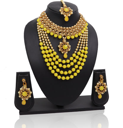 A yellow and gold coloured pearl choker necklace set with matching earrings and a mangtikka presented on a mannequin.