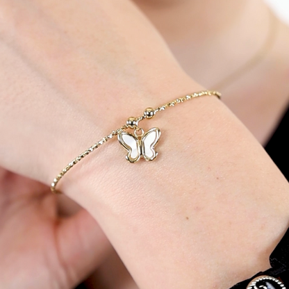 A gold bracelet with a butterfly charm on a person's wrist.