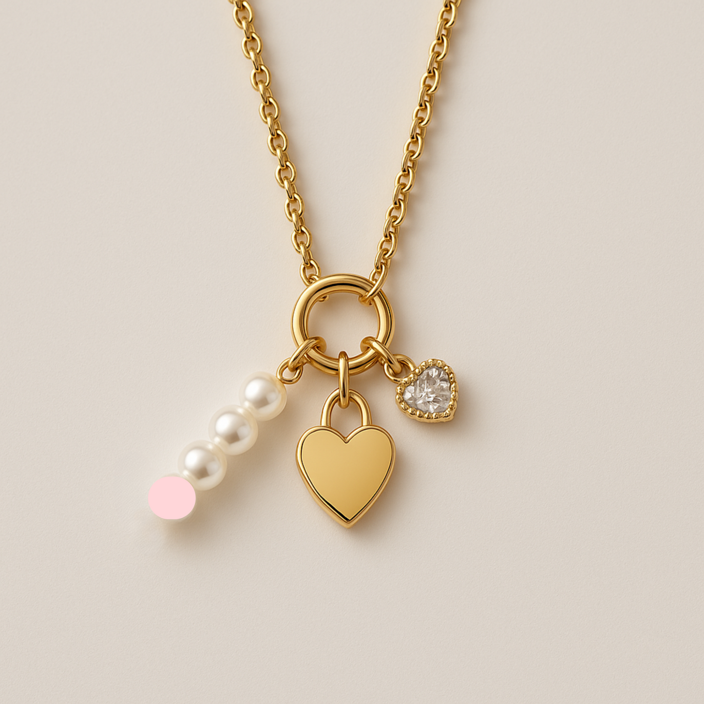 Gold necklace with heart, lock, and pearl charm on a beige background