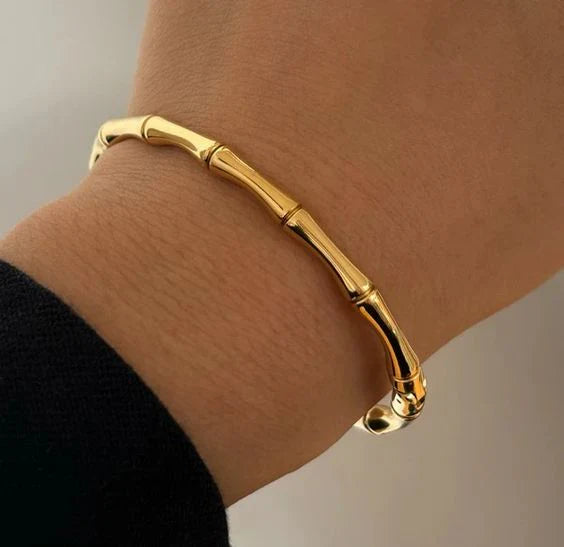 A close-up image of a person wearing an 18Kt gold bamboo design bracelet.