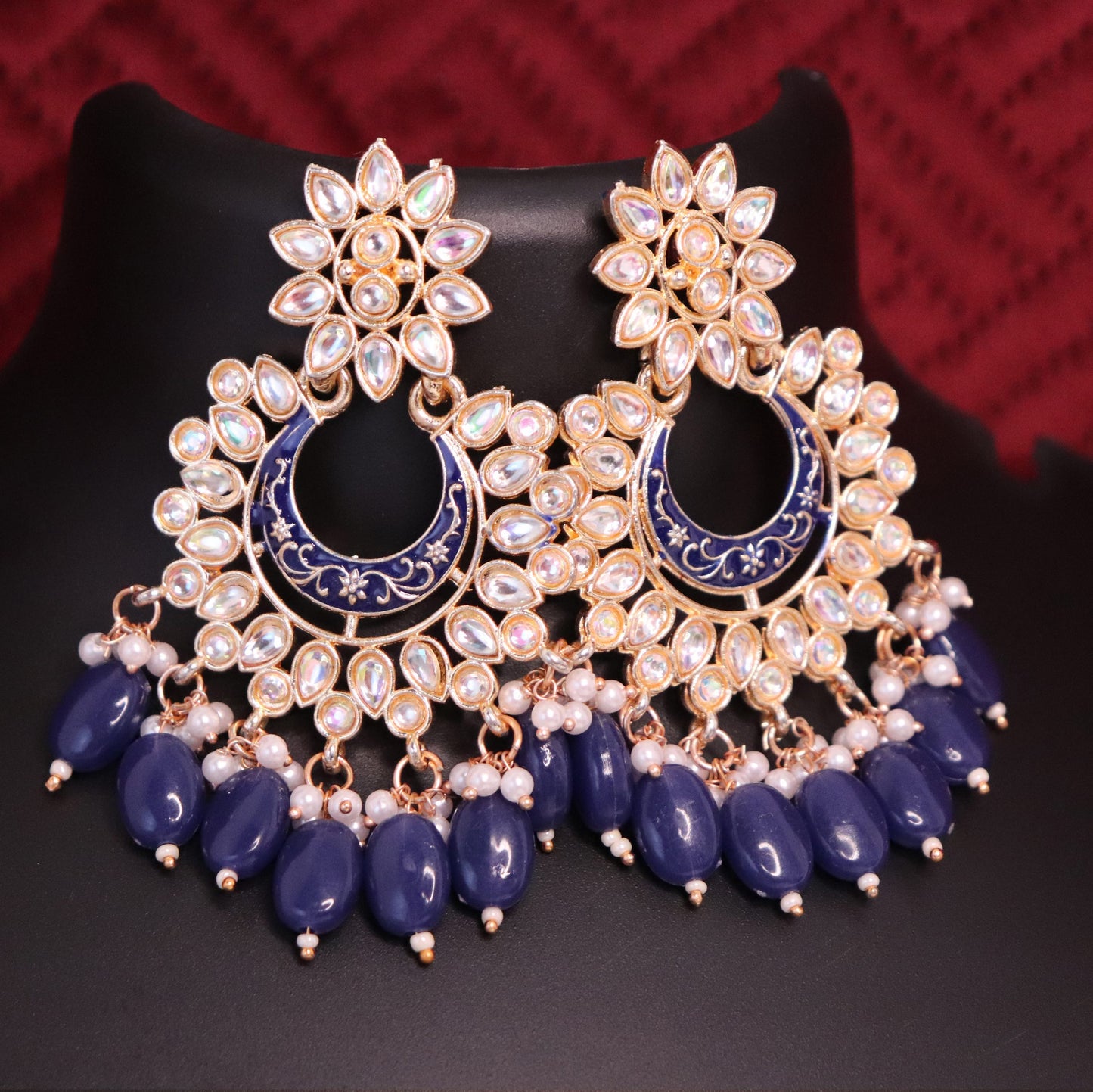 A pair of Chandbali earrings featuring a meenakari kundan style with dark blue color accents and pearl drops.