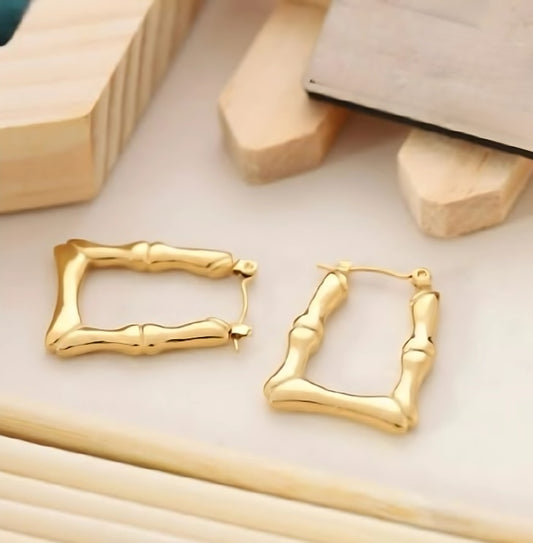 A pair of 18K gold plated U-Link hoop earrings on a wooden surface.