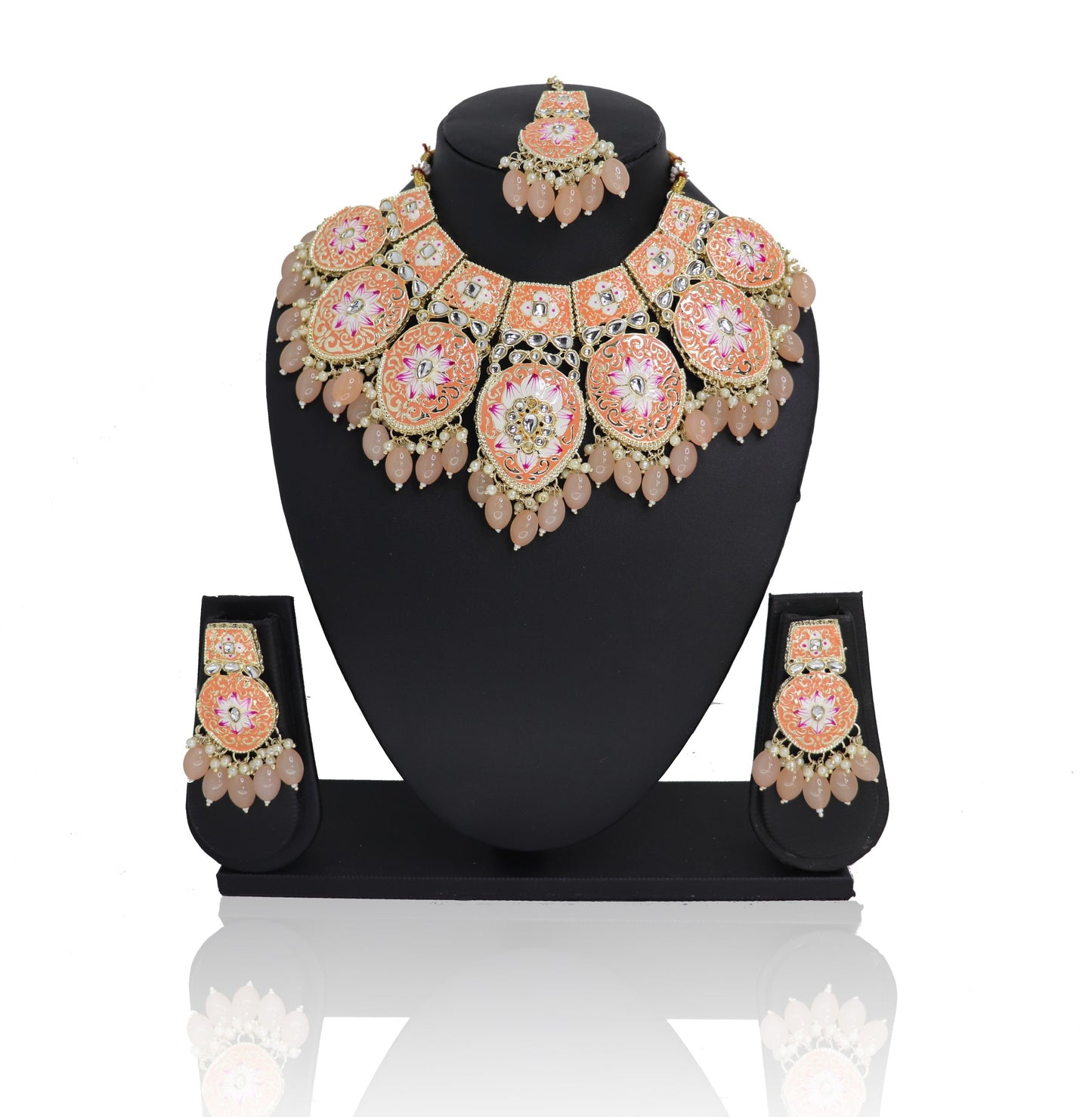 A jewelry set displayed on a mannequin, consisting of a necklace, earrings, and a maangtikka, with a floral design in peach and green colors.