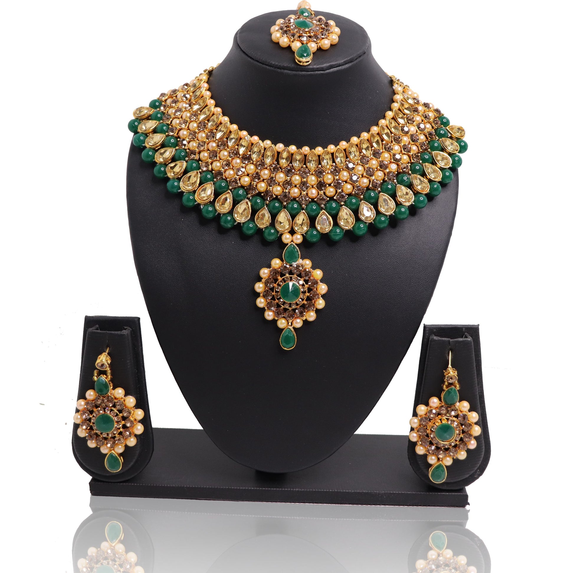 A set of jade and gold-colored jewelry including a necklace, earrings, and a maangtikka, displayed on a black stand.