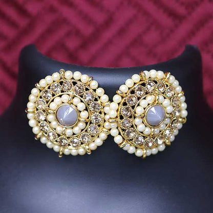 A pair of grey kundan stud earrings displayed on a black stand against a red background.