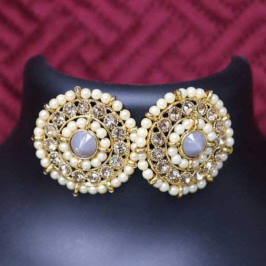 A pair of grey kundan stud earrings displayed on a black stand against a red background.