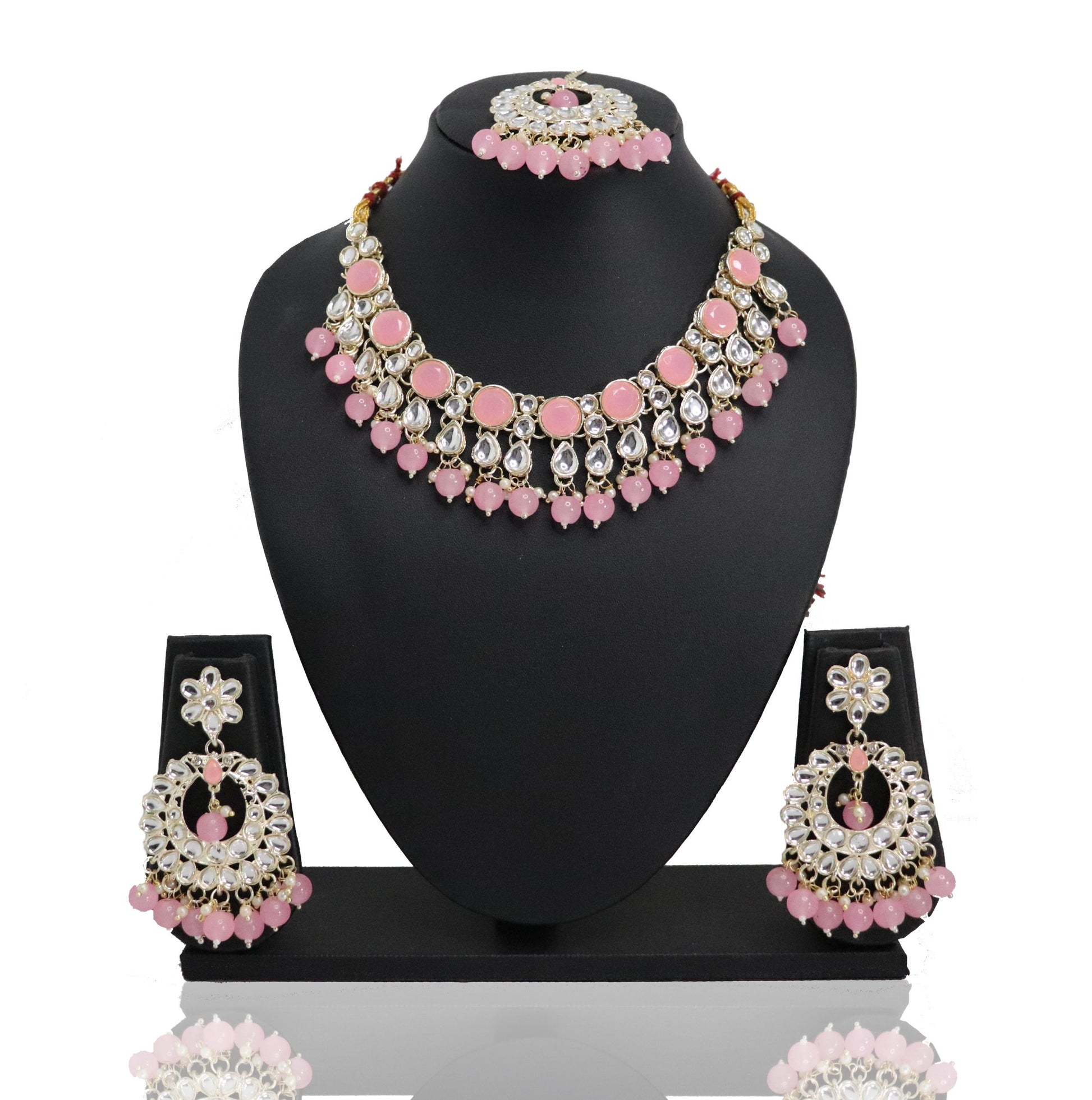 A pink and gold choker set with a necklace, earrings, and a mangtikka displayed on a mannequin bust.