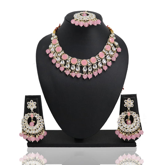 A pink and gold choker set with a necklace, earrings, and a mangtikka displayed on a mannequin bust.