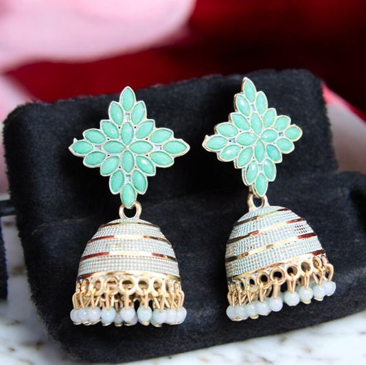 A pair of floral handcrafted jade earrings with green enameled flowers and gold-tone metalwork, displayed on a black cushion.