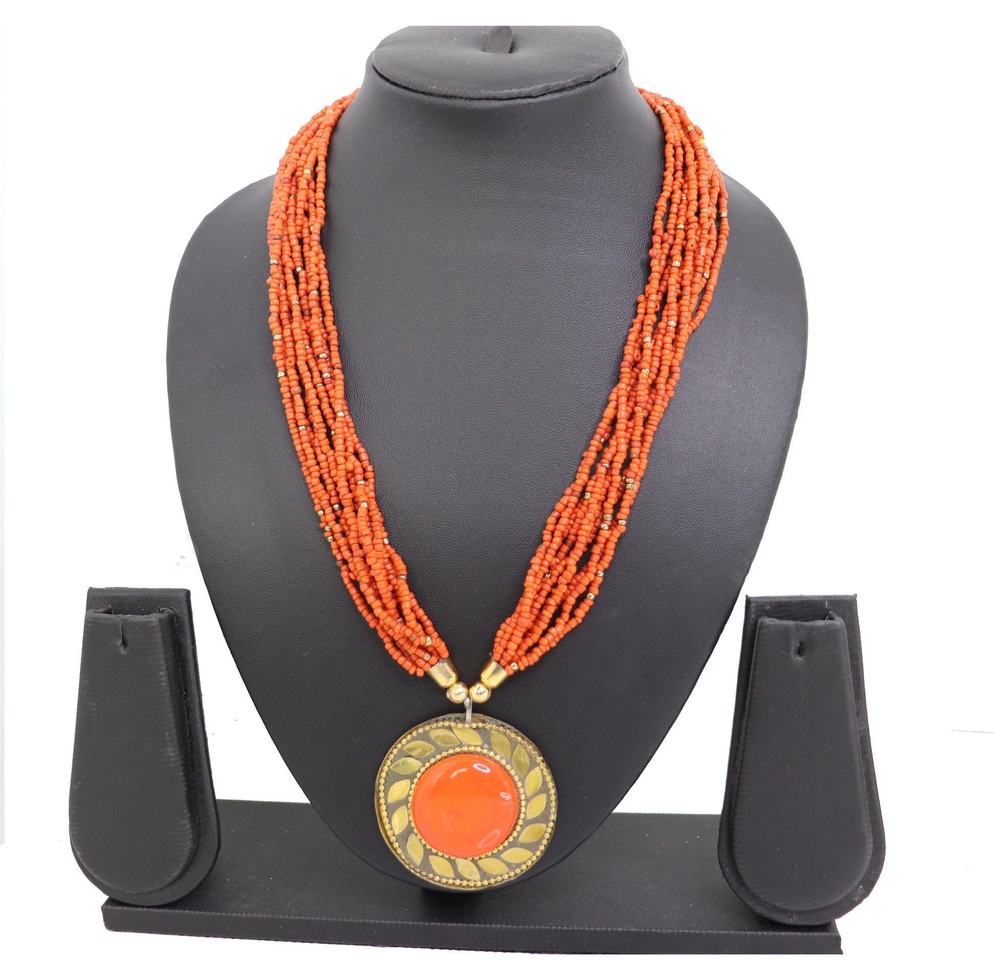 An orange beaded necklace with a central pendant, displayed on a mannequin bust.