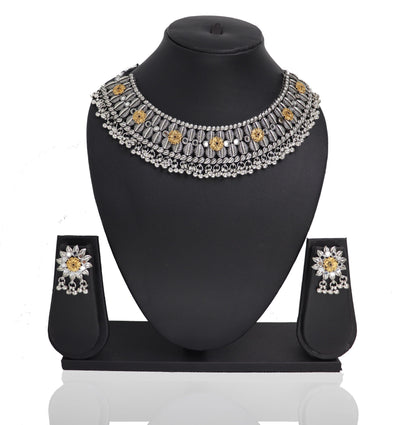 An oxidised silver choker necklace Set with a floral design and a pair of matching earrings displayed on a stand.