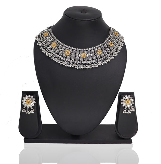 An oxidised silver choker necklace Set with a floral design and a pair of matching earrings displayed on a stand.