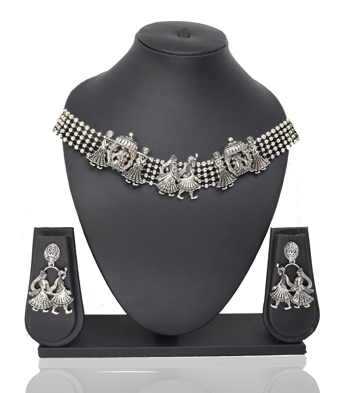 A silver choker necklace with a floral pattern and a pair of matching earrings displayed on a mannequin bust.