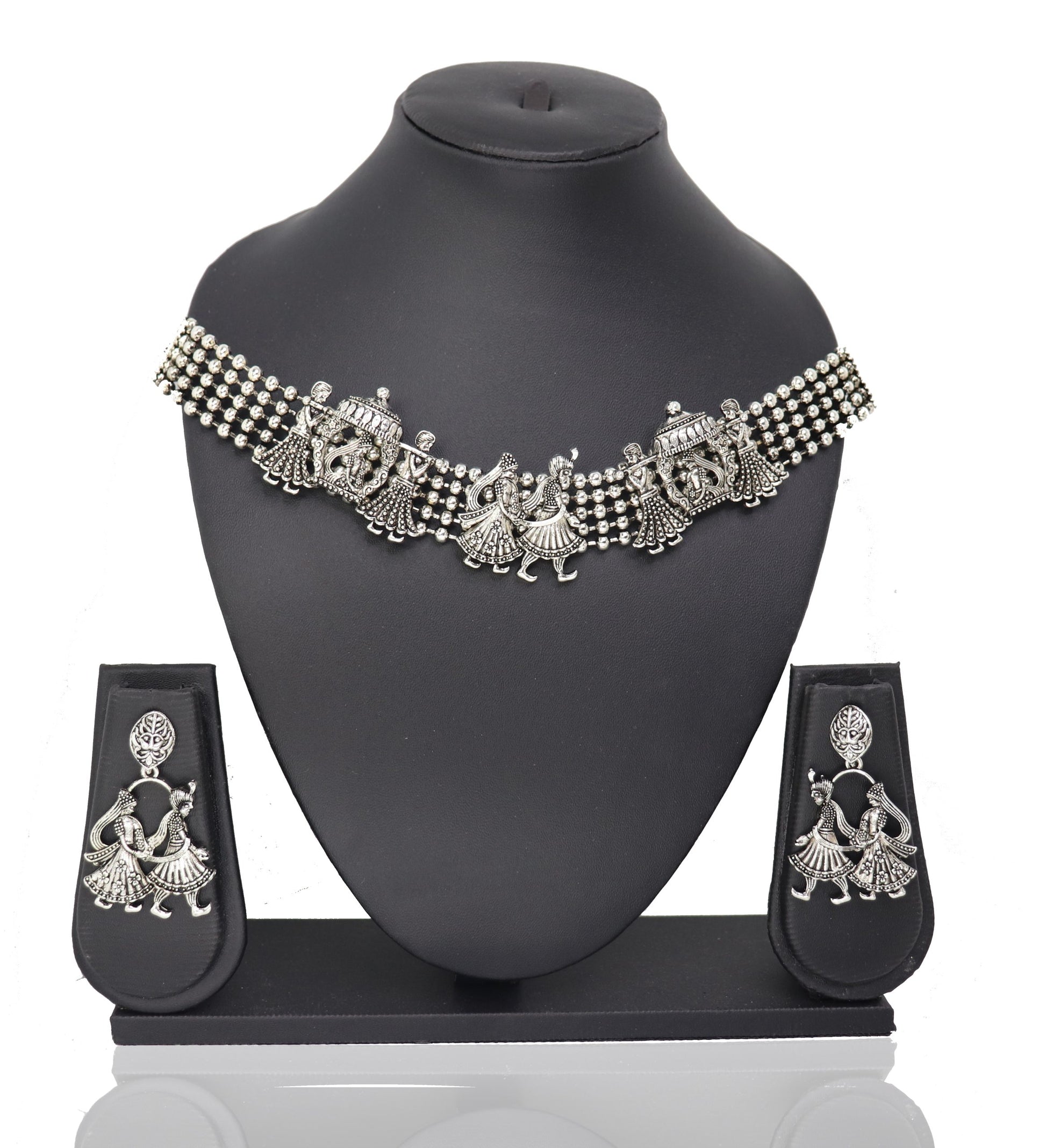 A silver choker necklace with a floral pattern and a pair of matching earrings displayed on a mannequin bust.