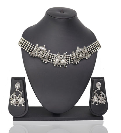 A silver choker necklace with a floral pattern and a pair of matching earrings displayed on a mannequin bust.
