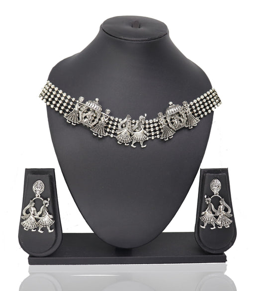 A silver choker necklace with a floral pattern and a pair of matching earrings displayed on a mannequin bust.
