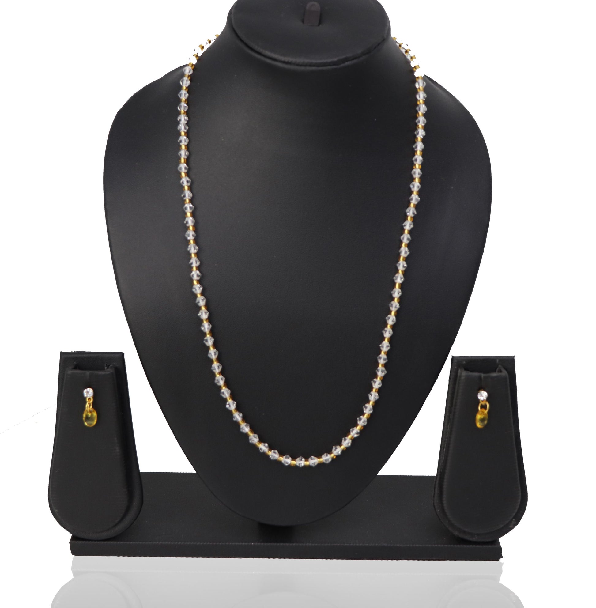 A necklace and three earrings set displayed on a mannequin, featuring white beads and gold-colored accents.