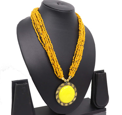 A yellow beaded necklace with a pendant featuring a similar yellow color, displayed on a black mannequin bust.